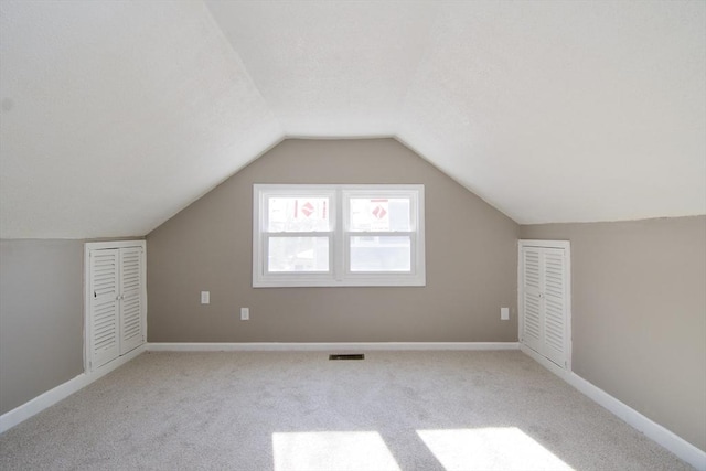 additional living space with light carpet and vaulted ceiling