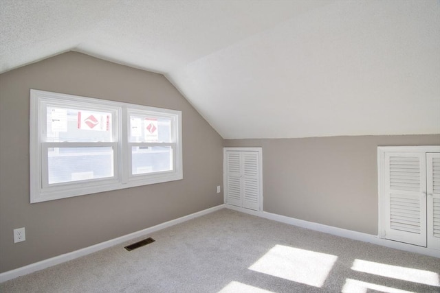 bonus room featuring vaulted ceiling and light colored carpet