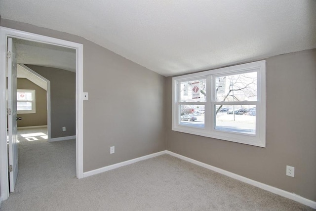 carpeted empty room with vaulted ceiling