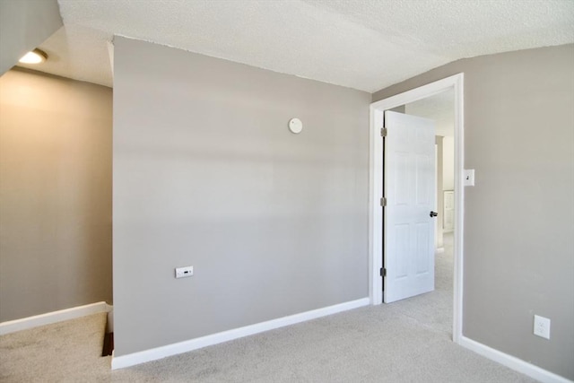 carpeted empty room featuring lofted ceiling and a textured ceiling