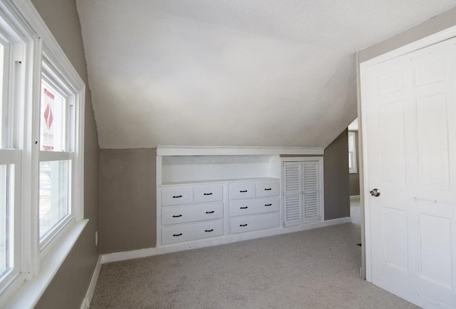 additional living space with vaulted ceiling and light carpet