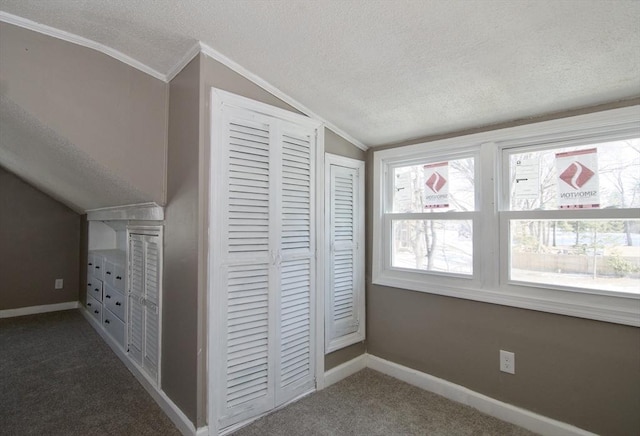 unfurnished bedroom with crown molding, lofted ceiling, dark carpet, and a textured ceiling