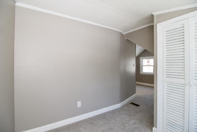 corridor featuring lofted ceiling, crown molding, light colored carpet, and a textured ceiling