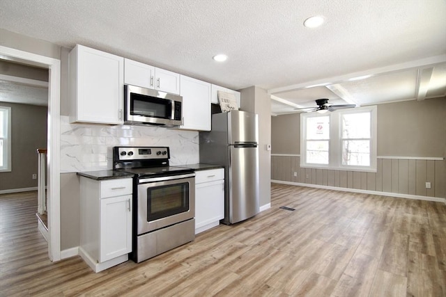 kitchen with white cabinetry, a textured ceiling, light wood-type flooring, appliances with stainless steel finishes, and backsplash