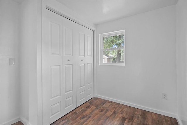 unfurnished bedroom featuring a closet and dark wood-type flooring