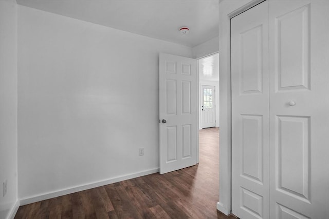 unfurnished bedroom with a closet and dark wood-type flooring