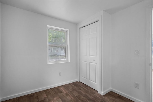 unfurnished bedroom with dark hardwood / wood-style flooring and a closet