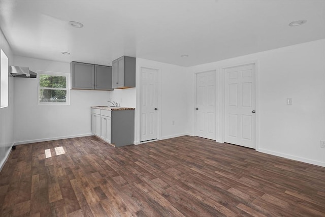 kitchen featuring gray cabinetry, dark hardwood / wood-style flooring, wall chimney exhaust hood, and sink