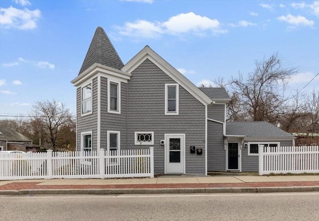 view of front of house with a shingled roof and a fenced front yard