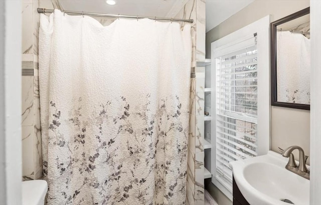 bathroom featuring a shower with shower curtain, toilet, and a sink