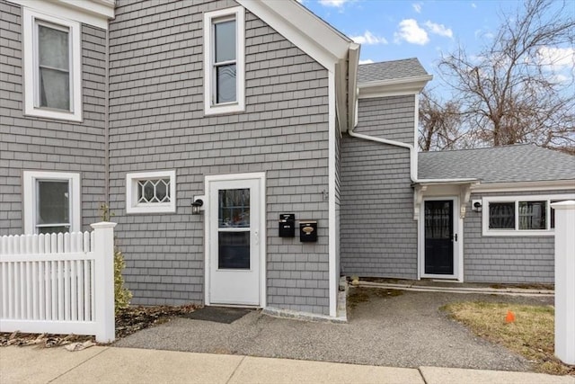 exterior space with fence and roof with shingles