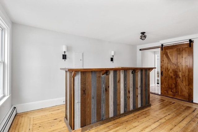 bar with baseboards, a barn door, a baseboard heating unit, and light wood-type flooring