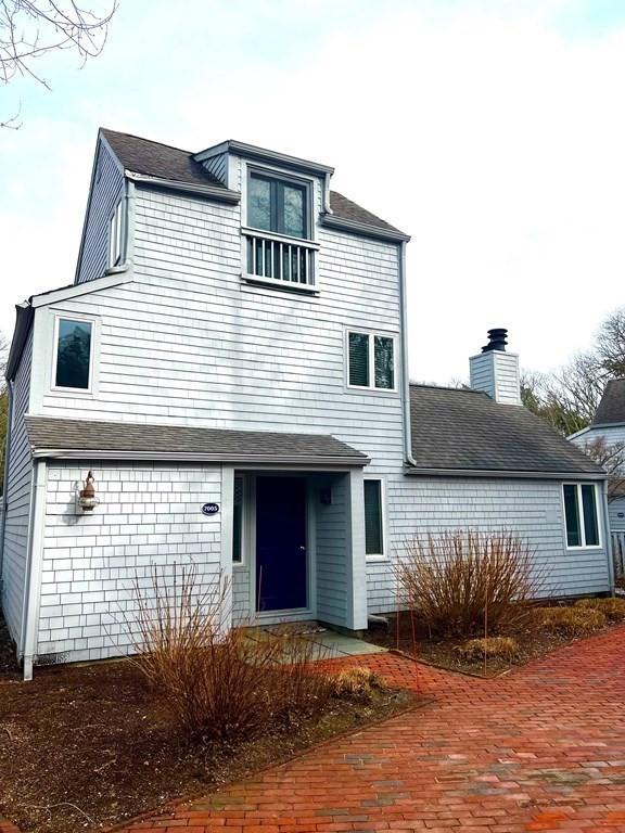 view of front of home featuring roof with shingles, a chimney, and a gambrel roof