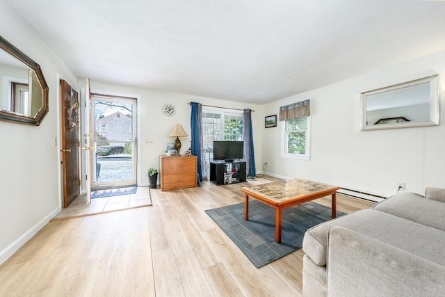 living room with a baseboard heating unit and light hardwood / wood-style flooring