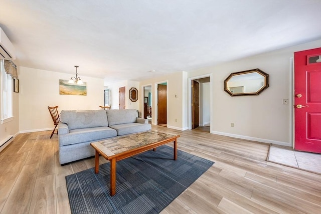 living room with an inviting chandelier, a wall mounted air conditioner, and light wood-type flooring