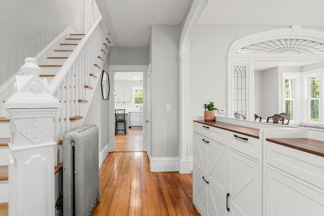 23 Schoolhouse Rd, Templeton, MA 01468 - bar area with radiator heating unit, light wood-type flooring, baseboards, arched walkways, and stairs