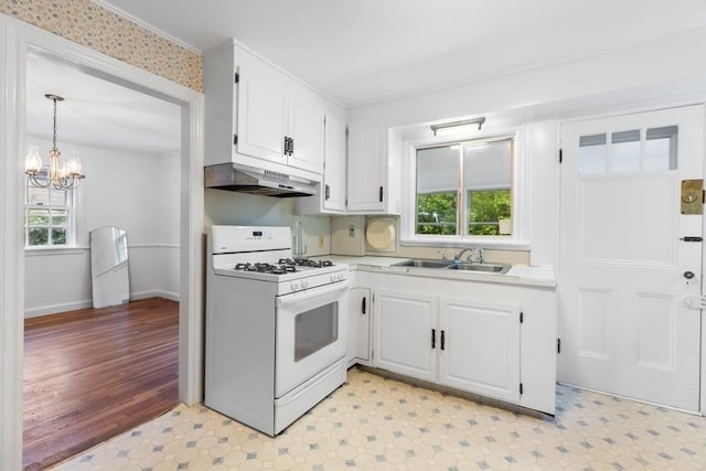 kitchen with white range with gas stovetop, a sink, under cabinet range hood, a chandelier, and white cabinets