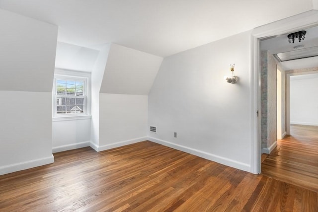 additional living space with baseboards, lofted ceiling, and wood finished floors