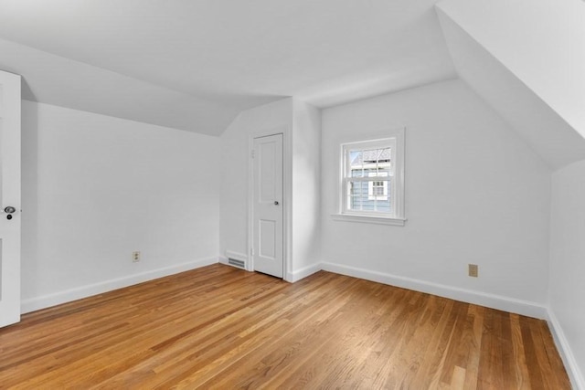 additional living space with lofted ceiling, light wood-style flooring, and baseboards