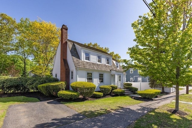 dutch colonial featuring a chimney and fence