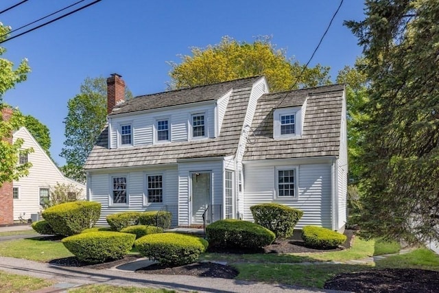 colonial inspired home with a chimney and a gambrel roof