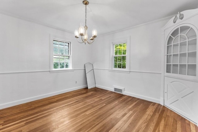 empty room with crown molding, a chandelier, light wood-style flooring, and baseboards