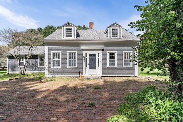 cape cod home featuring roof with shingles and a chimney