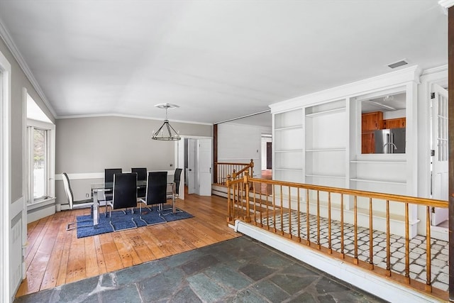 interior space featuring visible vents, ornamental molding, an inviting chandelier, lofted ceiling, and wood finished floors