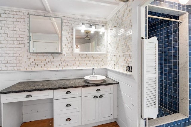bathroom featuring crown molding, vanity, and a tile shower