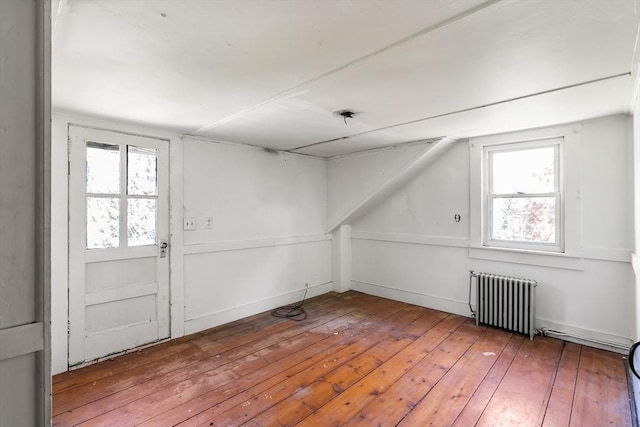 bonus room with a wealth of natural light, radiator heating unit, and hardwood / wood-style flooring