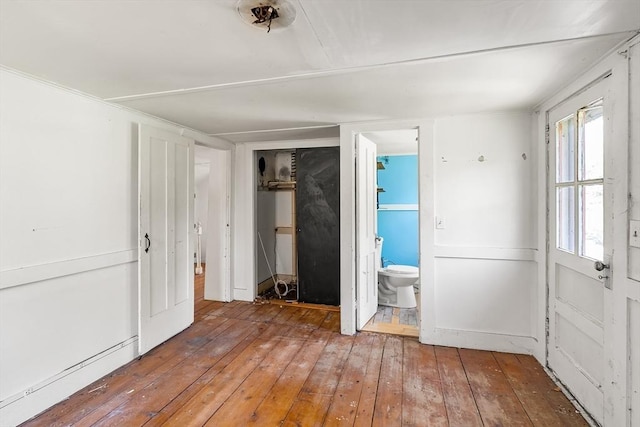 unfurnished bedroom with connected bathroom and hardwood / wood-style floors