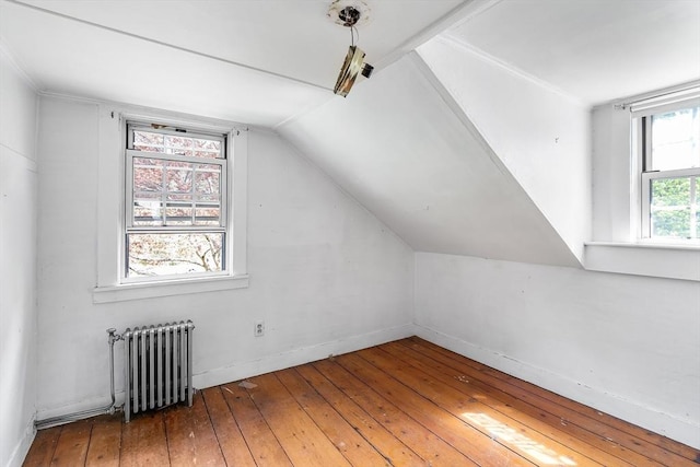 bonus room with baseboards, lofted ceiling, radiator heating unit, and hardwood / wood-style floors