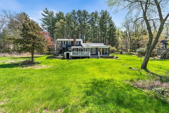 rear view of property with a wooden deck, a chimney, and a yard