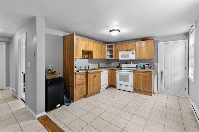 kitchen with white appliances, baseboards, baseboard heating, light countertops, and light tile patterned floors