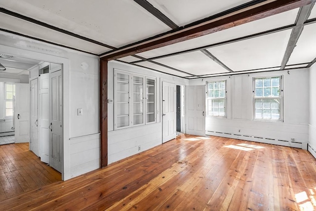 empty room featuring wood-type flooring and a baseboard radiator