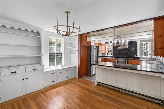 kitchen featuring appliances with stainless steel finishes, a sink, light wood-style floors, a chandelier, and a baseboard heating unit