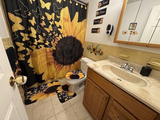 bathroom featuring tile patterned flooring, vanity, tile walls, and toilet