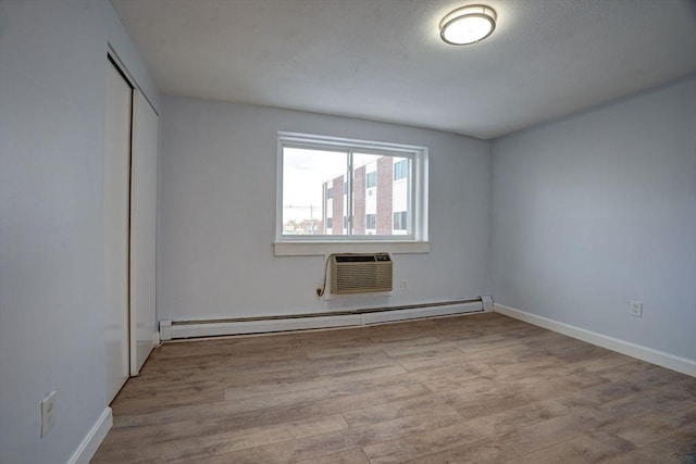 unfurnished bedroom featuring a wall mounted air conditioner, a baseboard radiator, a closet, and light wood-type flooring