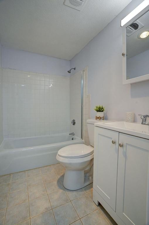 full bathroom with tile patterned floors, toilet, a textured ceiling, vanity, and tiled shower / bath combo