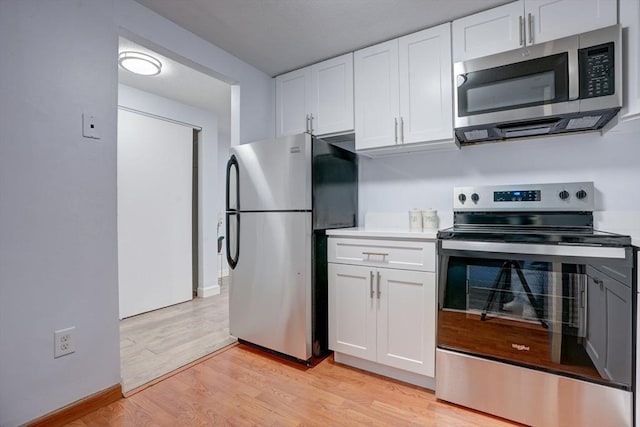 kitchen featuring stainless steel appliances, white cabinetry, and light hardwood / wood-style floors