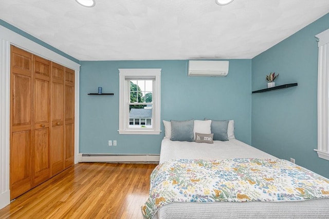 35 Warren Ave, Reading, MA 01867 - bedroom featuring a baseboard heating unit, light wood-style floors, a wall mounted air conditioner, a closet, and baseboards