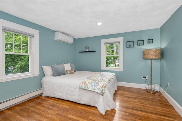 35 Warren Ave, Reading, MA 01867 - bedroom featuring a wall mounted air conditioner, a baseboard radiator, wood finished floors, and baseboards
