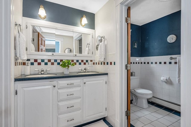 35 Warren Ave, Reading, MA 01867 - full bath with baseboard heating, tile walls, tile patterned flooring, double vanity, and toilet