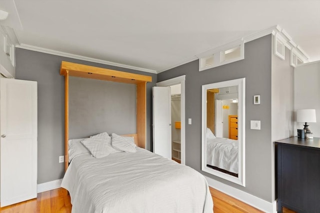 150 Prospect St Unit 3, Gloucester, MA 01930 - bedroom with light wood-type flooring, crown molding, and a walk in closet