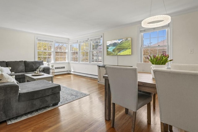 living room featuring crown molding, a baseboard heating unit, and wood finished floors