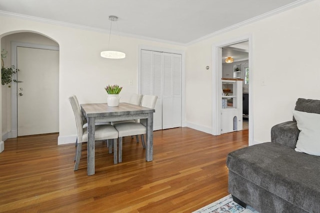 dining area featuring light wood-type flooring, arched walkways, baseboards, and ornamental molding