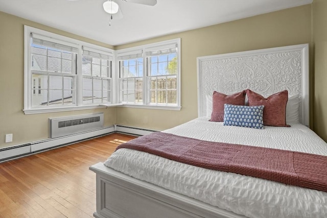 bedroom featuring a baseboard radiator, ceiling fan, and wood finished floors