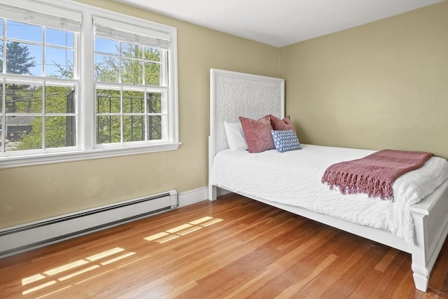 bedroom with a baseboard heating unit and wood finished floors
