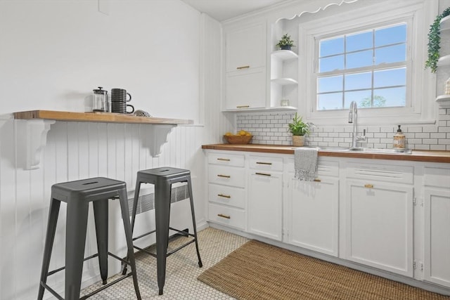 kitchen featuring open shelves, white cabinetry, and butcher block countertops