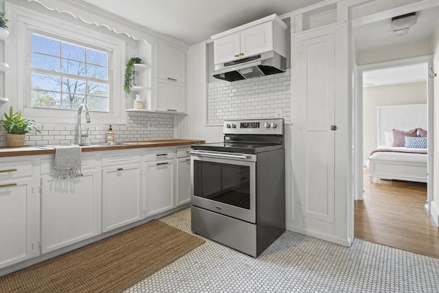 kitchen with stainless steel electric range oven, white cabinets, a sink, wood counters, and under cabinet range hood